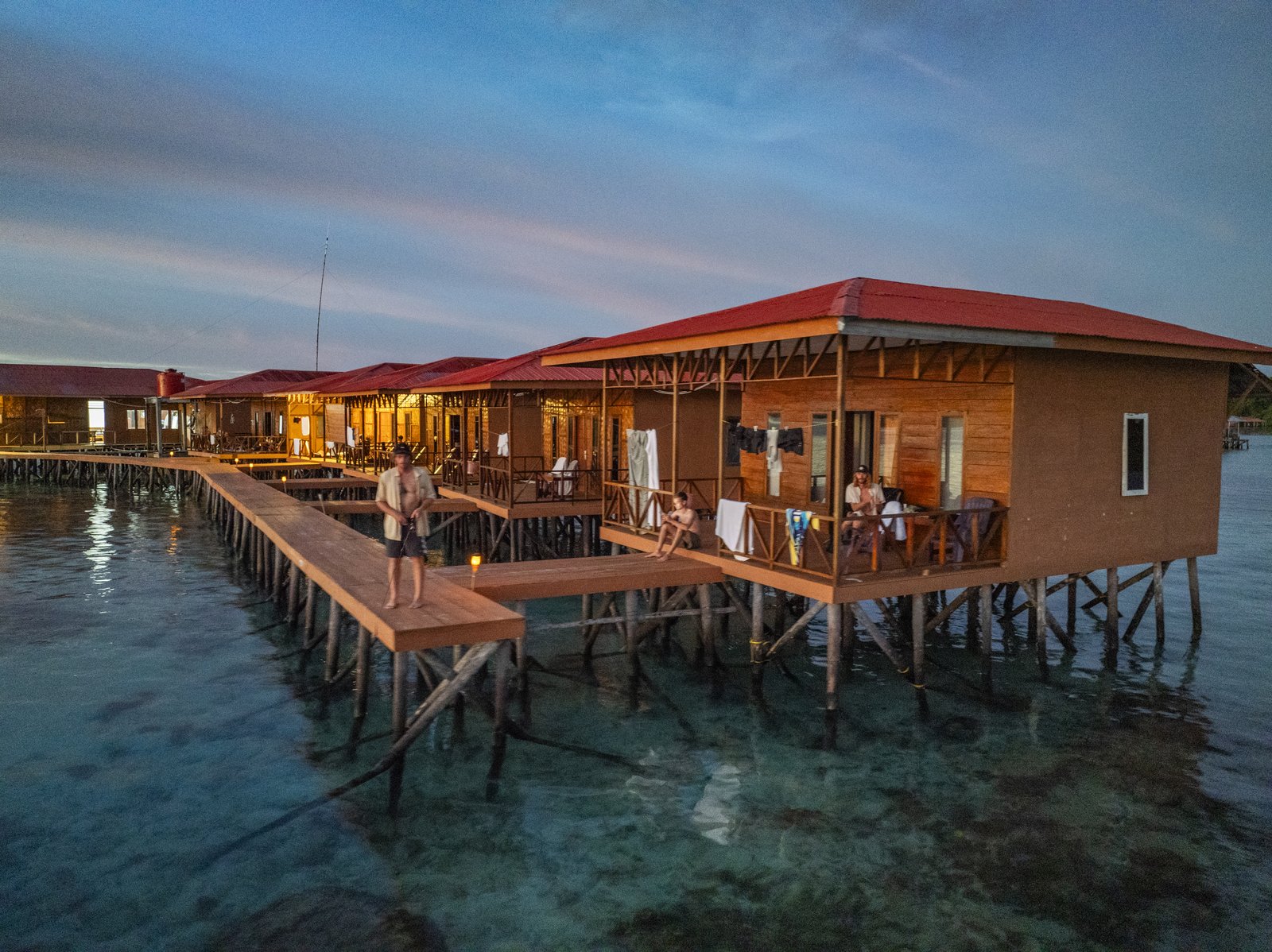 The villas and connecting timber walkway above clear water at blue hour