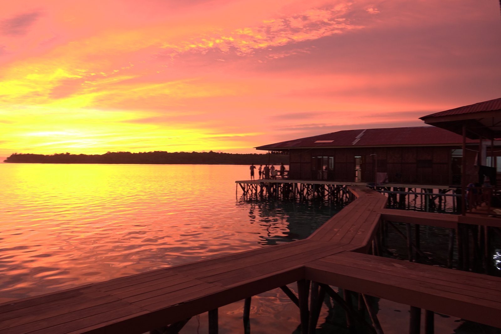 An orange sunset over the water beside the villas and timber walkway
